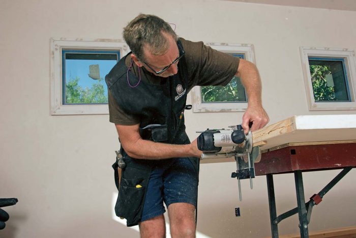 Cut a groove. Using a fence and a 3⁄8-in. straight bit, cut a groove in the bottom of the door for the plastic floor guide that keeps the door centered in the pocket.