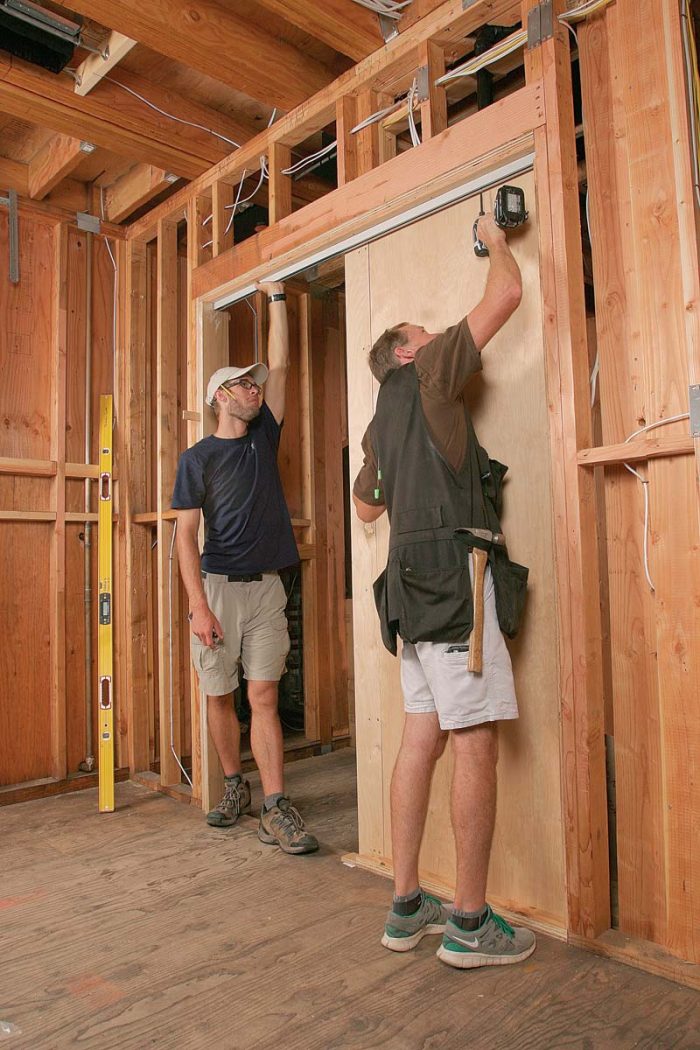 Fasten the track to two layers of 3⁄4-in. plywood attached to the bottom of the structural header.