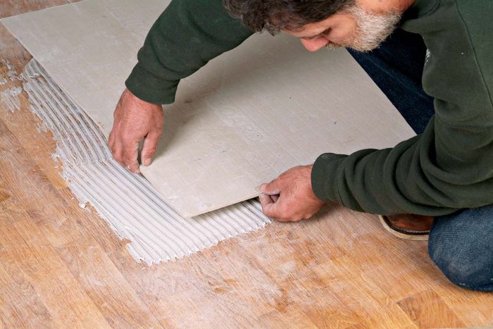 Comb the thinset and lay the backerboard over the sanded vinyl floor.